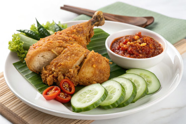Вкуснейшее блюдо Ayam Penyet, подаваемое со свежими ломтиками огурца и острым соусом чили на банановом листе - RomanZ