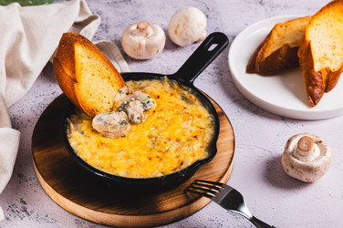 Нарезанные соломкой грибы со сливками и сырной корочкой жарятся на сковороде на столе - Elena Rui
