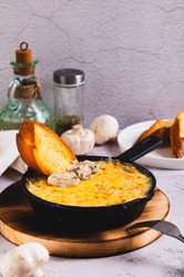Вкусная нарезанная соломкой колбаска с грибами и сыром, обжаренная на сковороде на столе (вертикальный вид) - Elena Rui