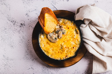 Крупный план аппетитной нарезанной соломкой колбаски с грибами и сыром на сковороде, вид со стола - Elena Rui