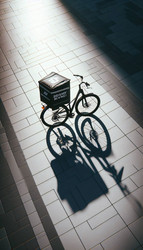 Эффектный вид сверху на велосипед для доставки с большой фирменной термосумкой, припаркованный на залитой солнцем городской площади; велосипед отбрасывает длинный, созданный искусственным интеллектом снимок - yuyu
