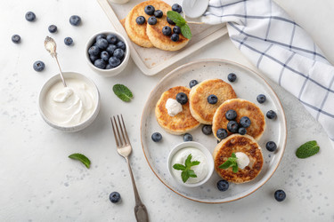 Вкусные блинчики с черникой и йогуртом на светлом фоне. Генеративный ИИ - RomanZ