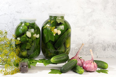 Маринованные огурцы в банке с чесноком и укропом на кухонном столе, деревенский урожай, рецепт домашнего маринования, огурцы и ингредиенты для маринования, концепция домашнего консервирования, здоровая и натуральная еда - svetlanabalyn