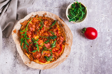 Вкусная пицца в пите с помидорами, колбасой, сыром и рукколой на столешнице - Elena Rui