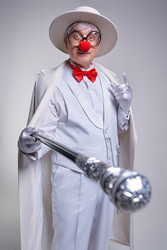 Сlown in a white cloak and hat extends his cane towards the camera and points his finger up - Serg Zastavkin