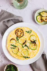 Вкусный омлет из кабачков с сыром и зеленью на тарелке, расположенной на столешнице в вертикальном положении - Elena Rui