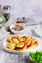 Ломтики цукини, запеченные с помидорами, сыром и чесноком на тарелке, подаются на стол в вертикальном положении - Elena Rui