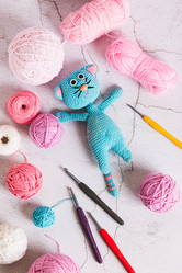 Вязаный игрушечный кот и разноцветные шарики для вязания крючком на столешнице в вертикальном положении - Elena Rui