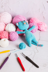 Вязаный игрушечный кот и разноцветные шарики для вязания крючком на столе в вертикальном положении - Elena Rui