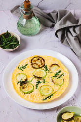 Вкусный омлет из кабачков с сыром и зеленью на тарелке на столе в вертикальном положении - Elena Rui