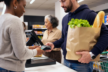 Мужчина расплачивается умными часами на кассе продуктового магазина - Pressmaster