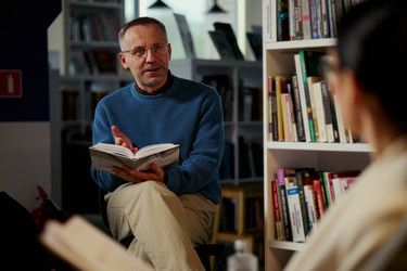 Мужчина средних лет ведет обсуждение книги в общественной учебной группе - DragonImagesAsia