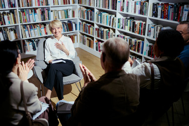 Женщина средних лет получает аплодисменты во время обсуждения книги в сообществе - DragonImagesAsia