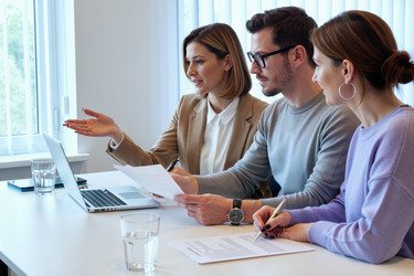 Коллеги по бизнесу работают за ноутбуком на встрече в офисе - DragonImagesAsia