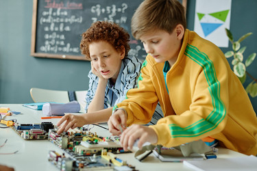 Мальчики-подростки собирают компьютерное оборудование в классе Stem - SeventyFour