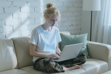 Focused Woman Working on Laptop on Sofa at Home Office - DragonImagesAsia
