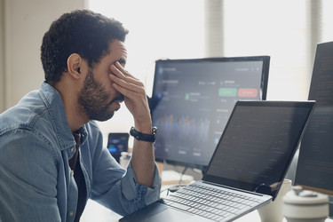 Мужчина закрывает лицо во время работы в офисе информационных технологий - SeventyFour