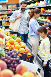 Счастливая семья покупает свежие фрукты в продуктовом отделе супермаркета - Pressmaster