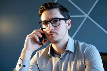 Портрет мужчины в очках, разговаривающего по смартфону в офисе - DragonImagesAsia
