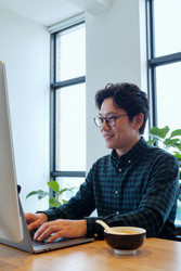 Азиат работает за ноутбуком во время ланча в офисе - DragonImagesAsia