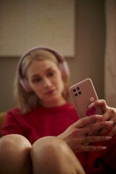 Женщина в наушниках использует смартфон для маркетинга в социальных сетях - DragonImagesAsia
