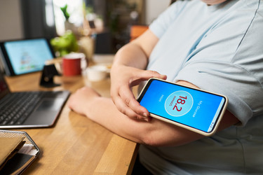 Женщина сканирует Cgm-датчик на руке с помощью смартфона, показывающий высокий уровень глюкозы - Pressmaster