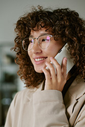 Улыбающаяся двухрасовая бизнесвумен разговаривает по смартфону в офисе - AnnaStills