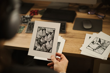 Мужчина с гравюрой в руках рассматривает портфолио фотографий за письменным столом - DragonImagesAsia