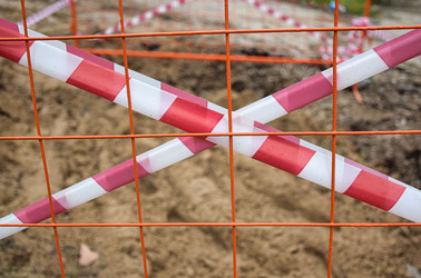 Ограждение из оранжевой сетки с красными и белыми предупреждающими полосами. Заграждение в виде полосатой красно-белой сигнальной ленты вокруг коммунальной ямы - Sveetlana