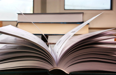 Открытая книга на столе на фоне других книг - nkaup
