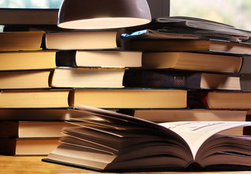 Открытая книга под лампой на фоне стопки книг - nkaup