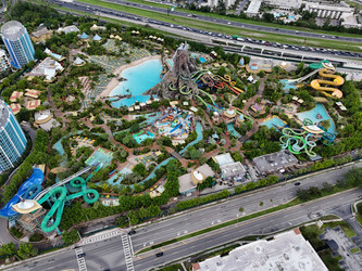 7 июля 2026 года полет беспилотника над аквапарком Volcano Bay с вулканом, бассейнами, горками и близлежащим движением на шоссе в Орландо, Флорида, США. g - EOS_Canon