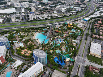 Вид с высоты птичьего полета на аквапарк Volcano Bay с вулканом, бассейнами, горками и близлежащим движением на шоссе в Орландо, Флорида, США. g - EOS_Canon