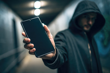 Таинственная фигура со смартфоном в руках в темной городской обстановке ночью - RomanZ