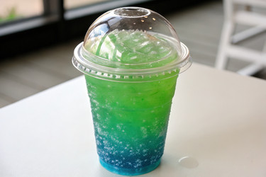 Красочная чашка Slurpee, наполненная зеленым и синим напитком Generative AI - RomanZ