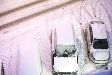 заснеженные автомобили, припаркованные на улице зимой, со слоем свежего снега, покрывающим транспортные средства, и следами шин, видимыми на снегу - Darya Petrenko