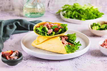 Вкусные тако с консервированным тунцом, огурцом, помидором и листьями салата на тарелке на столе - Elena Rui