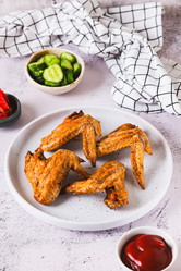 Аппетитные запеченные куриные крылышки с кетчупом на тарелке на столе, вид сверху - Elena Rui
