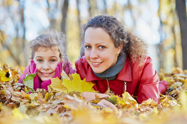 Mother and her little daughter lie in autumn park in drift - paha_l