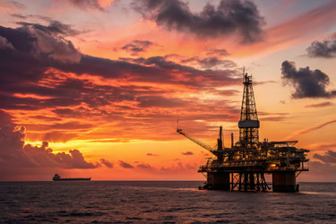закат над нефтяной вышкой с силуэтом корабля на фоне яркого неба в море - RomanZ
