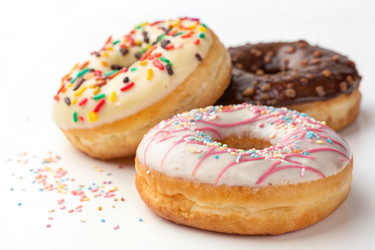 разноцветные пончики с посыпкой на белом фоне в яркой обстановке - RomanZ