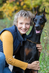 Smiling woman at jacket is hugging the dobermann in a park - paha_l