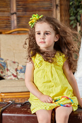 Little girl in yellow dress sits on old big ragged suitcase in room - paha_l