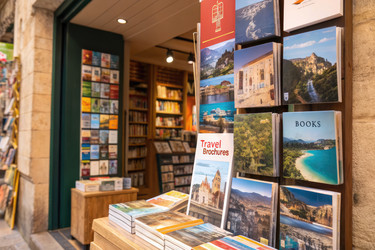 туристические брошюры и книги, выставленные перед необычным магазином в солнечном месте - RomanZ