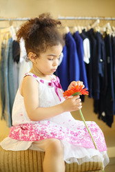 Pretty little girl with red flower sits at pouf in children - paha_l