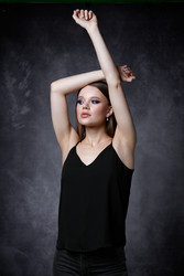 Портрет женщины в черной майке на бретельках и джинсах. женщина с поднятыми руками на сером фоне - Serg Zastavkin