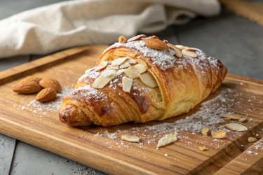вкусный миндальный круассан на деревянной доске с сахарной пудрой - RomanZ