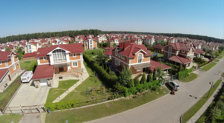 Вид с высоты птичьего полета на коттеджный городок рядом с лесом в солнечный летний день - paha_l