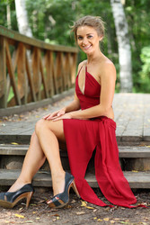 Beautiful girl in a red dress sitting on a wooden bridge - paha_l