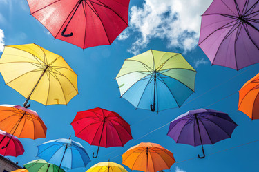 Разноцветные зонтики парят в голубом небе над оживленным уличным фестивалем - RomanZ
